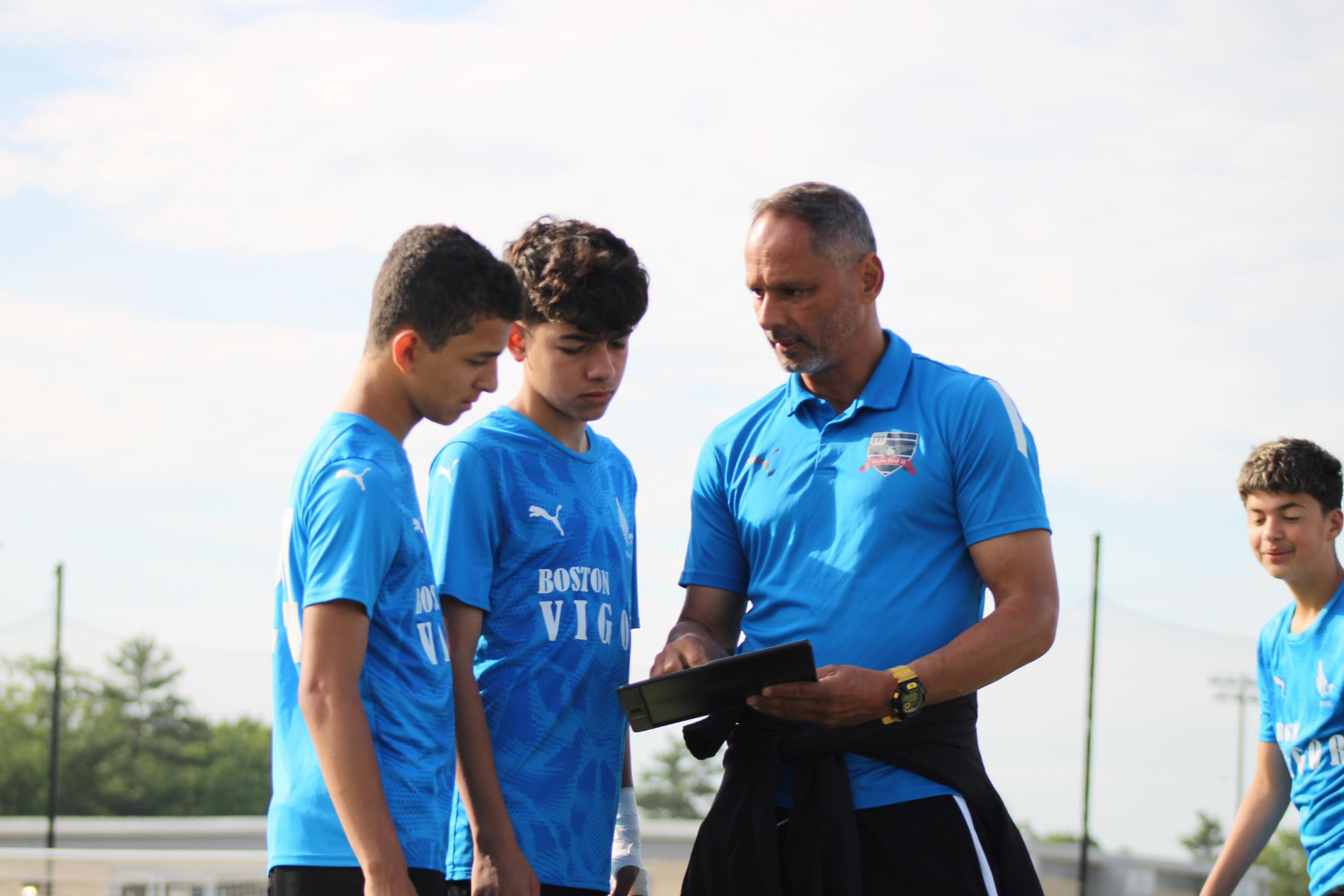 Coach Wilson Mineiro standing on the pitch at golden hour